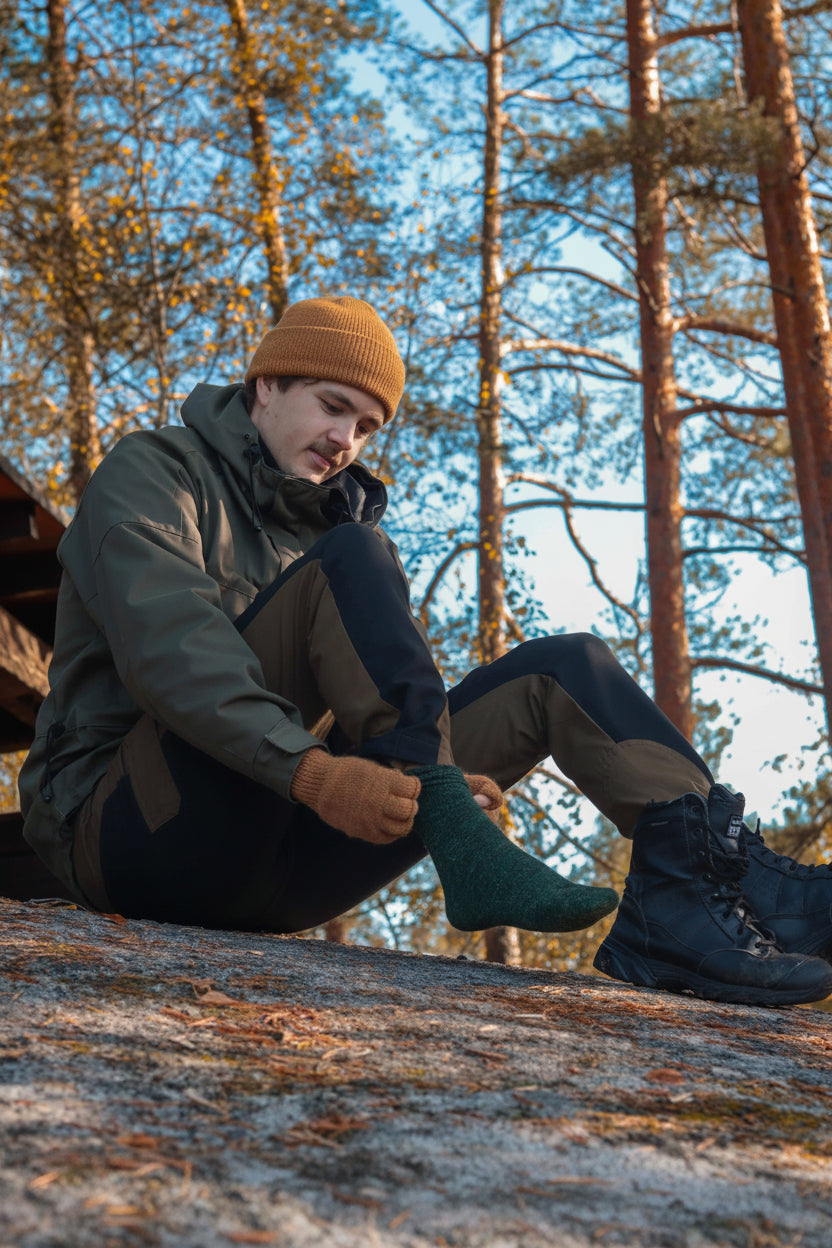 alpakanvilla_pulu_kynsikas_mies_pukee_sukkaa_metsässä