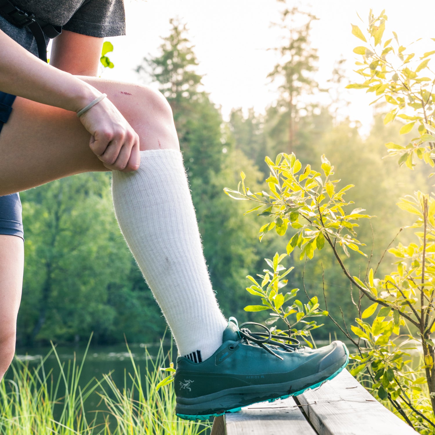Person wearing green shoes and white socks sitting on a wooden bench with a natural background
