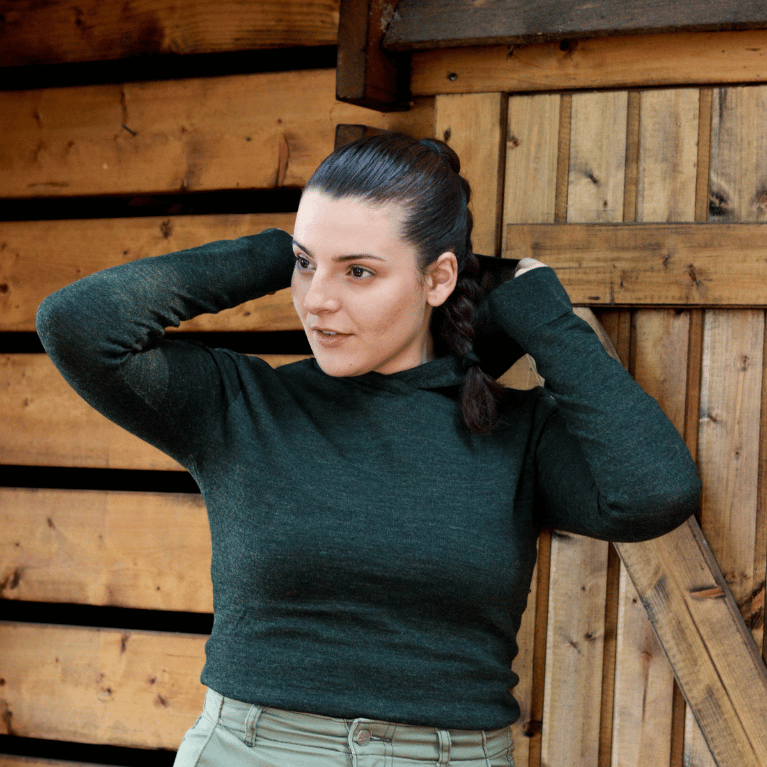 Vaeltaja100 alpacawool hoodie forestgreen woman holding the hood of her hoodie with her hands